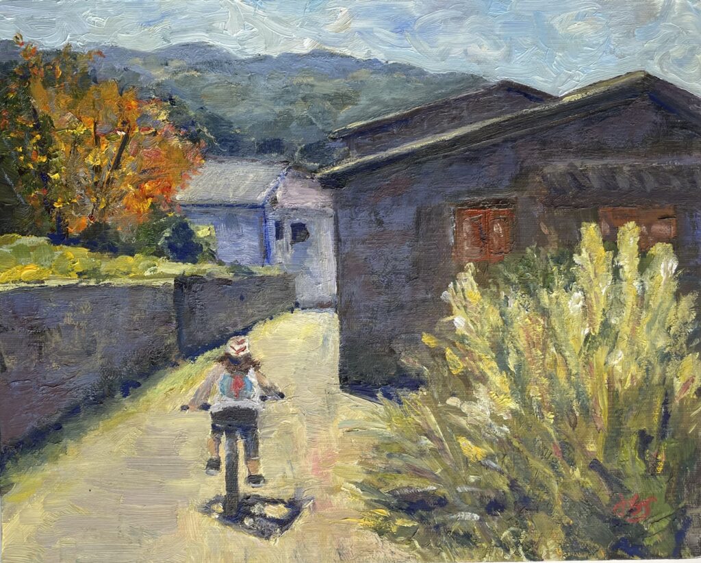 Oil painting of a cyclist riding away from the viewer on a narrow road between old stone houses. Mountains of Tuscany in the background.